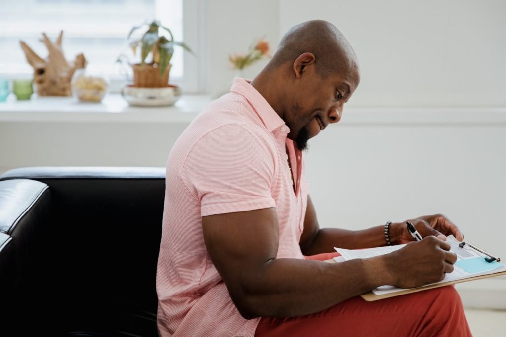 Adult writing on a clipboard indoors, focusing on mental health or office work.